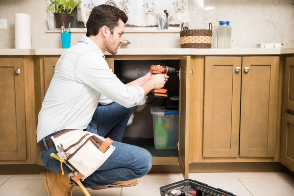 Jeune homme à tout faire utilisant une perceuse électrique — Photo