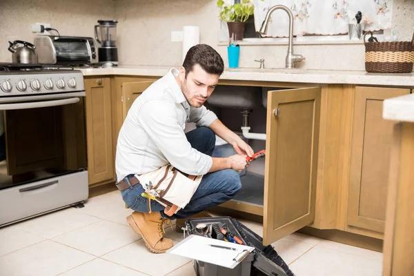 Мужчина-сантехник чинит раковину на кухне — стоковое фото