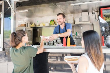 Girls buying hot dogs from food truck clipart