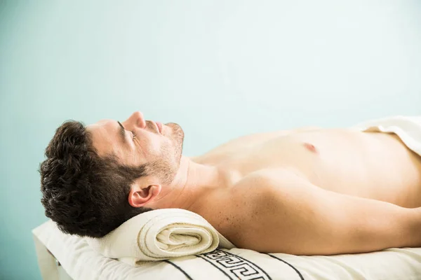 Homem deitado em uma cama de massagem — Fotografia de Stock