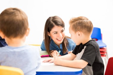 Bir sınıf bir boyama aktivite ile bir öğrenci yardım güzel İspanyol anaokulu öğretmeni portresi
