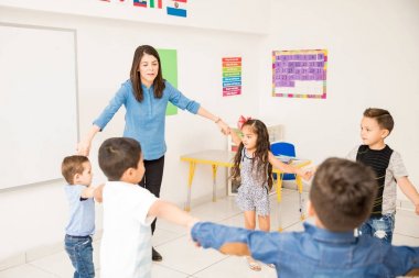 Öğrencileri ile elele ve sınıfta bir daire yapma okul öncesi öğretmeni