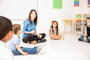 Şirin görünümlü genç kadın ise bir daire yapma ve sınıf katında oturan okul öncesi öğrencilerinin öğretim