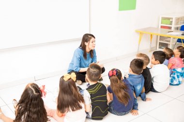 Grup okul öncesi öğrenci ve öğretmen sınıf katında oturan ve öğrenme