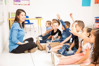 Güzel okul öncesi öğretmeni ve ellerini yükselterek ve biraz eğlenmeye okulda öğrenci grubu