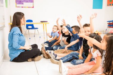 Bir grup okul öncesi öğrenci ellerini yükselterek ve okulda katılmaya çalışırken profil görünümü
