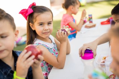 Bir grup arkadaşıyla ile öğle yemeği için bir elma yemek muhteşem bir Latin preschooler portresi