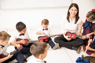 Öğrenciler okul öncesi içinde onların müzik aleti çalmayı gösterilen güzel bir İspanyol öğretmen portresi