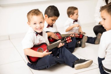 Bir sınıfta gitar çalmak ve onun müzik dersi zevk iyi görünümlü bir beyaz çocuk portresi
