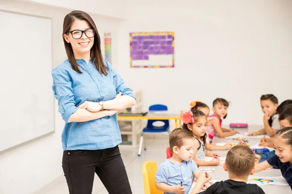 Nerdy Vorschullehrerin Steht Einem Klassenzimmer Voller Schüler Und Lächelt — Stockfoto