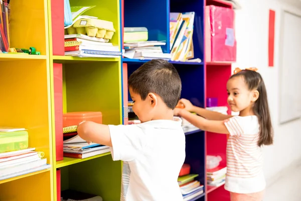 Δυο Παιδιά Προσχολικής Ηλικίας Αρπάζοντας Βιβλία Τους Ένα Ντουλάπι Στην — Φωτογραφία Αρχείου