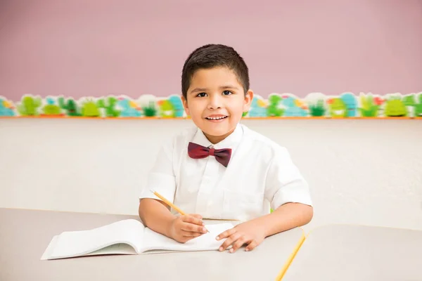 制服を着て 保育園でクラスを楽しんで良い探しているヒスパニックの子供の肖像画 — ストック写真