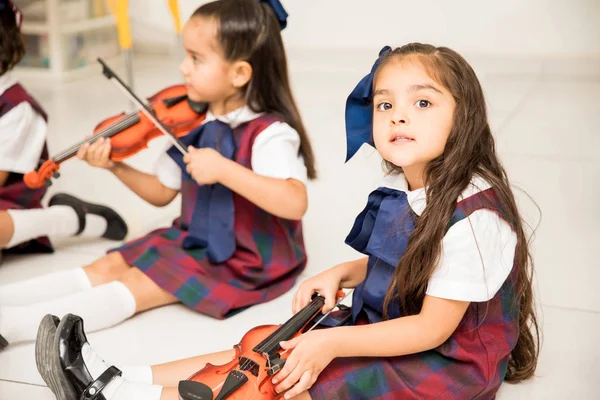 漂亮的小女孩在幼儿园的音乐课上拿着小小提琴和眼神交流 — 图库照片