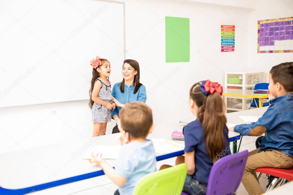 Beautiful little girl participating in class and reciting a poem in a preschool classroom