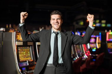 İyi görünümlü İspanyol bir adam kollarını yükseltmek ve kutlama bir takım sadece bir Casino para kazandı