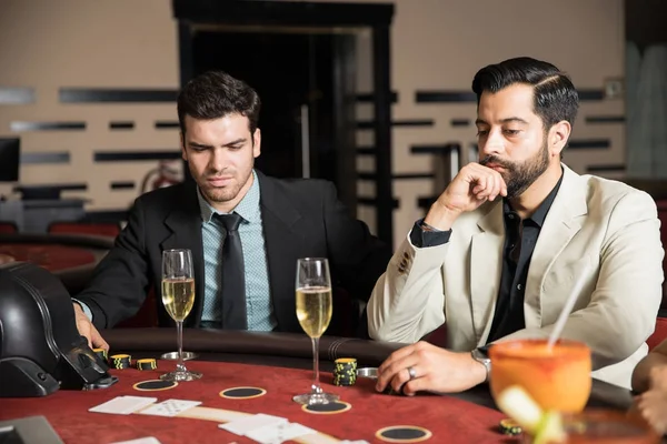 两个男人看着严重的 而喝香槟和打牌在赌场 — 图库照片