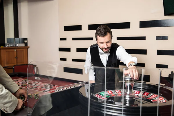 Guapo Distribuidor Casino Masculino Tomando Apuestas Gente Girando Ruleta — Foto de Stock