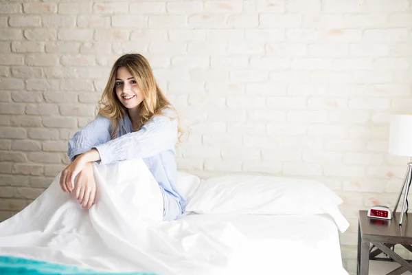 Ładna kobieta siedzi w łóżku — Zdjęcie stockowe
