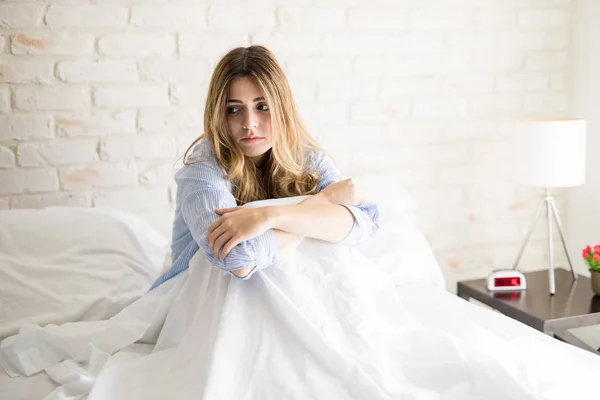 Femme inquiète assise dans son lit — Photo