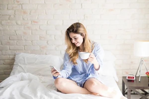 Latin woman drinking coffee in bed — Stock Photo, Image