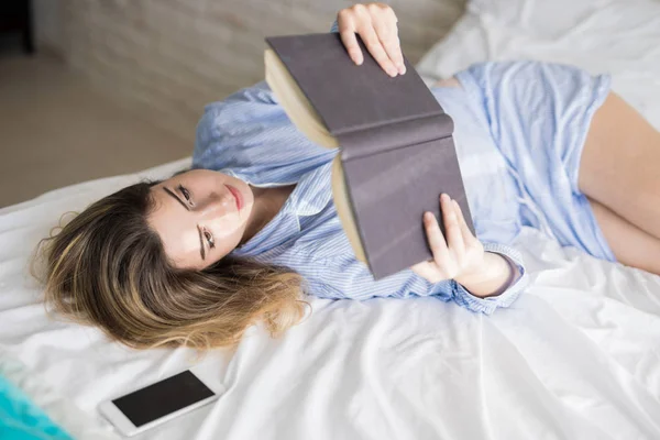 Az ágyban egy érdekes könyvet olvasni — Stock Fotó