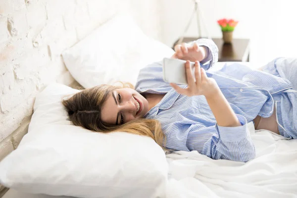 Mujer en pijama usando un smartphone — Foto de Stock