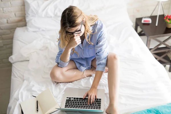 Frau liest E-Mails im Bett — Stockfoto