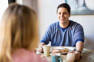 Bir restoranda kahvaltı yaparken onun kız arkadaşının elini tutarak yakışıklı genç