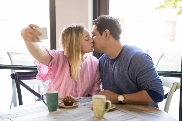 浪漫的年轻情侣接吻 在咖啡馆约会时带着手机自拍 — 图库照片