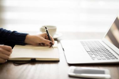 Masa üstünde laptop ile günlüğü üzerinde notlar yazma kadının yakın çekim