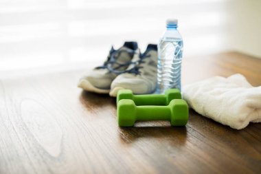 Fitness ve aktif yaşam tarzları kavramı. Halter, spor ayakkabı, bir şişe su ve havlu ahşap tablo