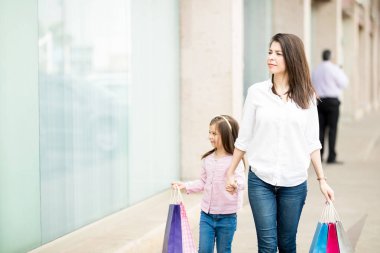 Kızı ve annesi Vitrin camekanlar boyunca renkli çanta ile yürüme 