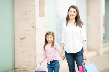 Vitrin camekanlar arka plan üzerinde renkli alışveriş torbaları ile anne ve kızı ayakta