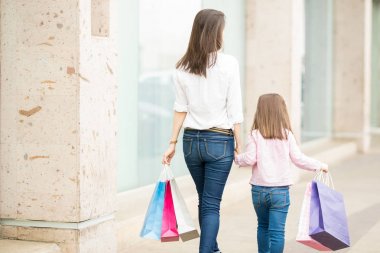 Anne ve kızı Vitrin camekanlar boyunca alışveriş torbaları ile yürüme arka görünümü