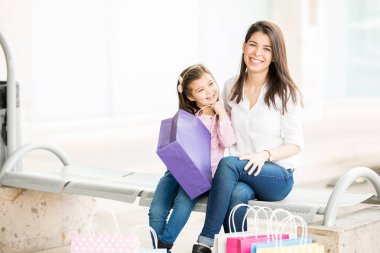 Anne ve kızı dış mall alışveriş torbaları ile oturan 