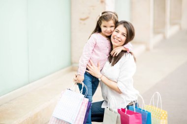 Anne ve kızı renkli alışveriş torbaları ile alışveriş merkezi yakınındaki sarılma