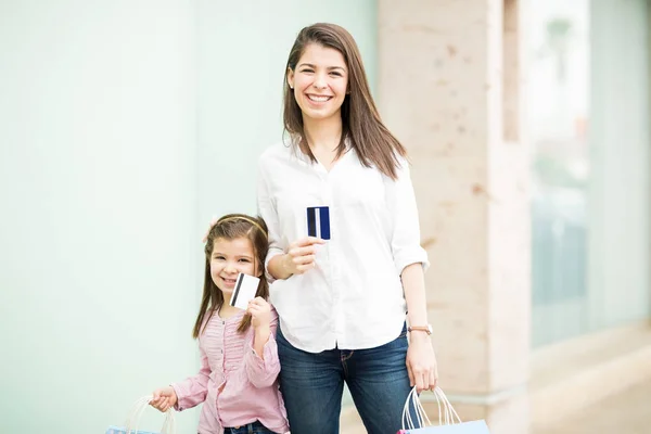 母亲和女儿在店面背景上展示信用卡 — 图库照片