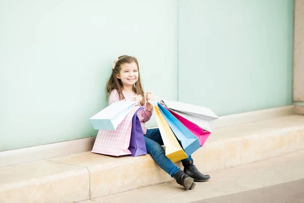 カラフルなショッピング バッグを店舗近くに座って女の子 — ストック写真