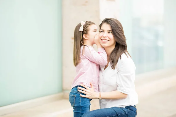 Daughter telling secret mother on storefront background