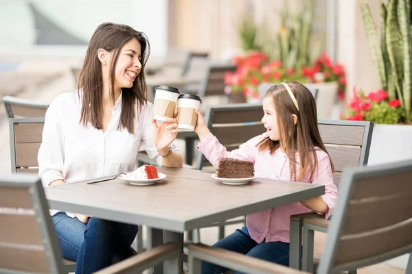 Mother and daughter making cheers with coffee in cafe