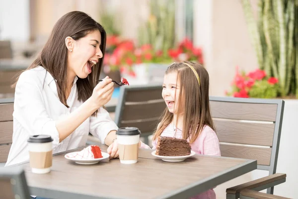 背景をぼかした写真のカフェで彼女の娘のケーキを餌の母 — ストック写真