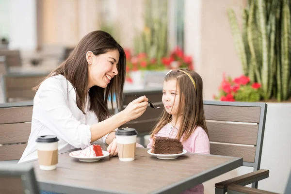 背景をぼかした写真のカフェで彼女の娘のケーキを餌の母 — ストック写真