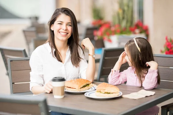 母亲和女孩坐在咖啡馆与汉堡桌上 — 图库照片