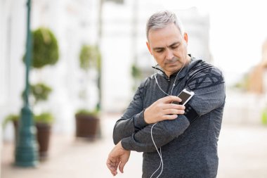 Orta yaş adam şehrin onun akıllı kol bandı üzerinde egzersiz için bir çalma listesi seçme