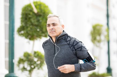 Şehirde çalışan ve bir akıllı telefon ile müzik dinlemek sağlıklı orta yaşlı adam