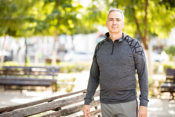 Portrait of active mature man standing outdoors in the park before doing some exercise