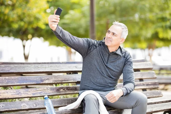 Muž Středního Věku Přičemž Selfie Při Sedí Lavičce Parku Cvičení — Stock fotografie