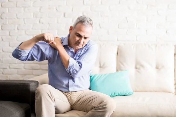 Hombre Mediana Edad Sentado Sofá Sosteniendo Hombro Doloroso Con Otra —  Fotos de Stock