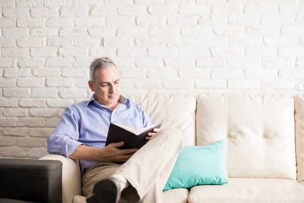 Bon Homme Mature Regardant Détendre Sur Canapé Livre Lecture Intérieur — Photo