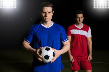 Topu ile rakip takım oyuncusu arkasında bir rekabet maç için sahada ayakta tutan uygun genç futbolcu